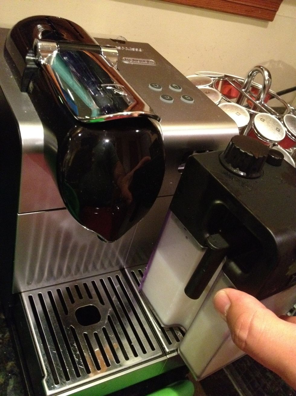 Insert milk container into slot behind the door you just opened. It just pushes straight back: there is a click/locking sensation when it is in the right place.