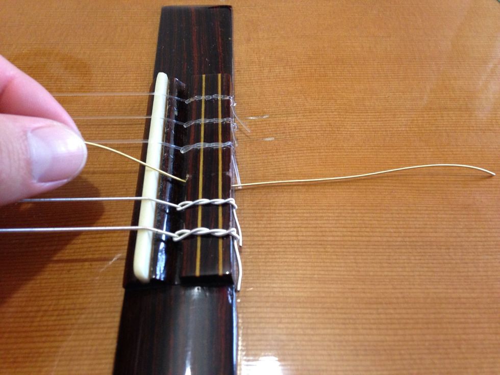 Insert one of the ends of the string in the bridge hole. Leave an 'excess' of 1.5 inches from the bridge.