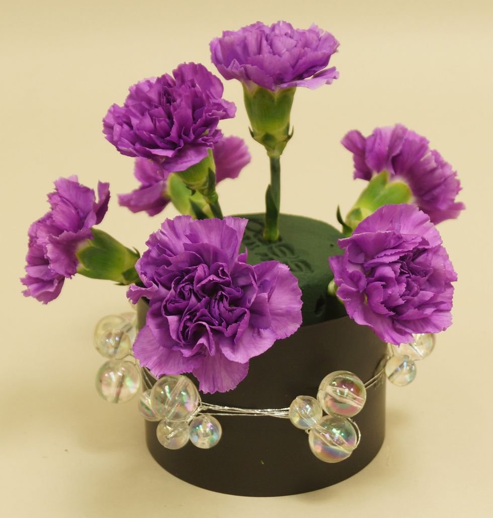 Insert stems of purple carnations into foam.