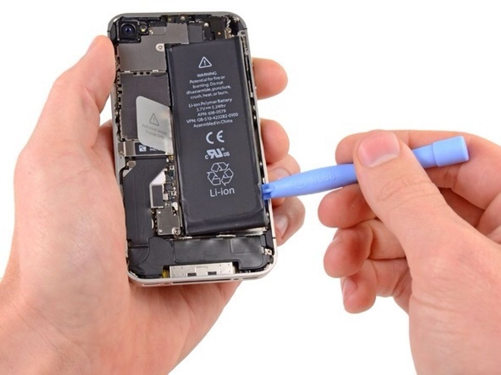 Insert the edge of a plastic opening tool between the battery and the outer case near the bottom left corner of the iPhone. Run the plastic opening tool along the edge of the battery and pry up.