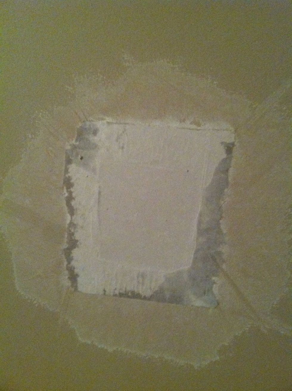 Insert the repair piece into the hole you prepared in the wall. Use a 12" drywall knife to push the piece in flush working the excess mud out from under the edges of the paper.