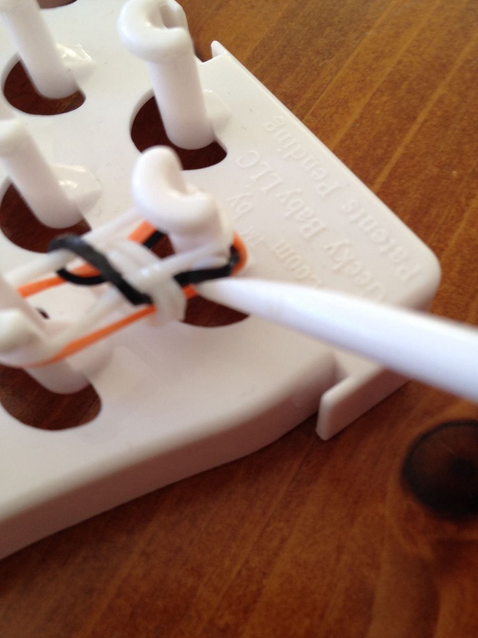 Insert your loom hook into the middle of the second band and grab the bottom band and pull it up and over to the middle