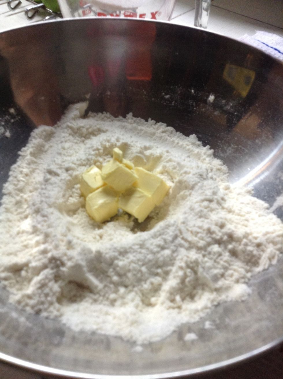 Inside the cleared area place the butter. I like cutting the bar in little cubes as they are easier to mix. Afterwards grab some of the mix from the sides and sprinkle the butter cubes with it.