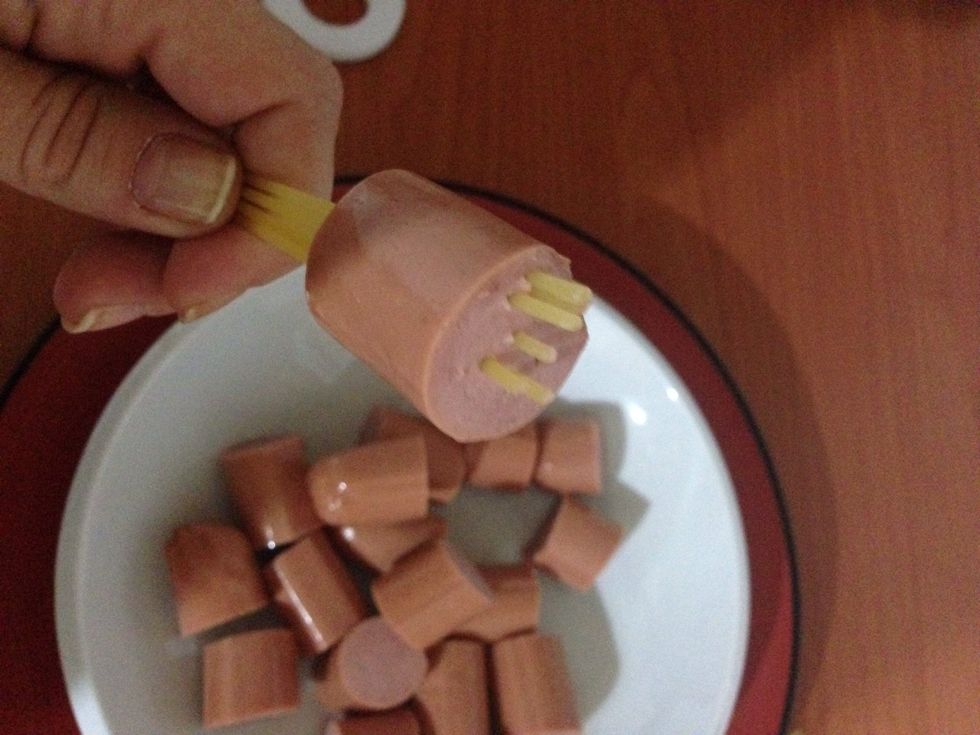 introduce 6 spaghetti on each piece of sausage (introducir 6 espaguetis en cada trozo de salchicha)