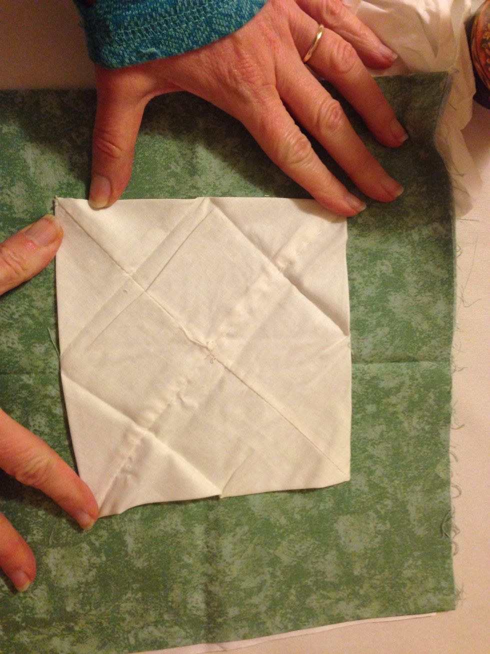 Iron the square flat. Then fold down the sides to make a smaller square.