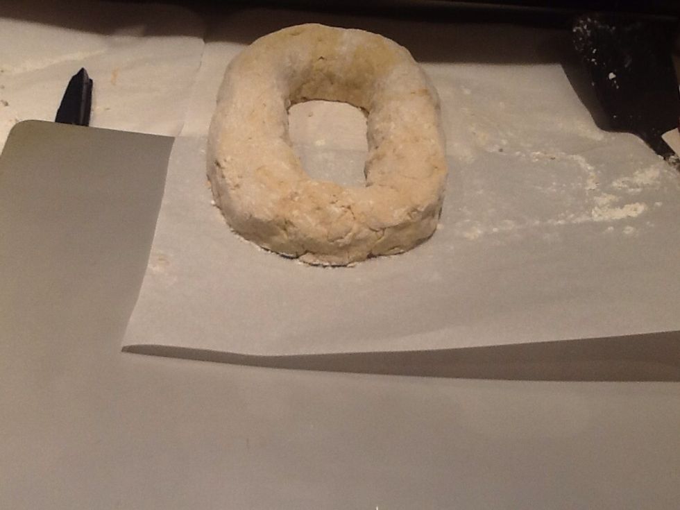 It is hard to move, so bring the ends together with the spatula assistance, pinch together, you can moisten inside one side. Use the parchment to slide it on the cookie sheet.  Cut the parchment paper