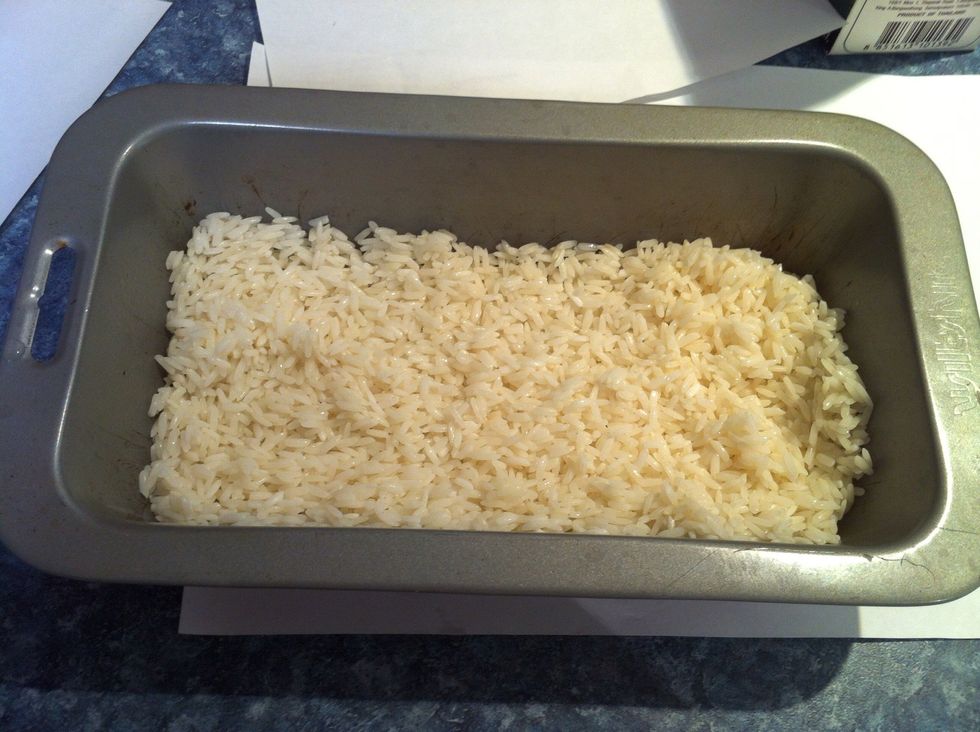 It's vital the pan is greased well otherwise you will have problems getting it out clean from the pan. Now add the drained rice evenly into the pan.