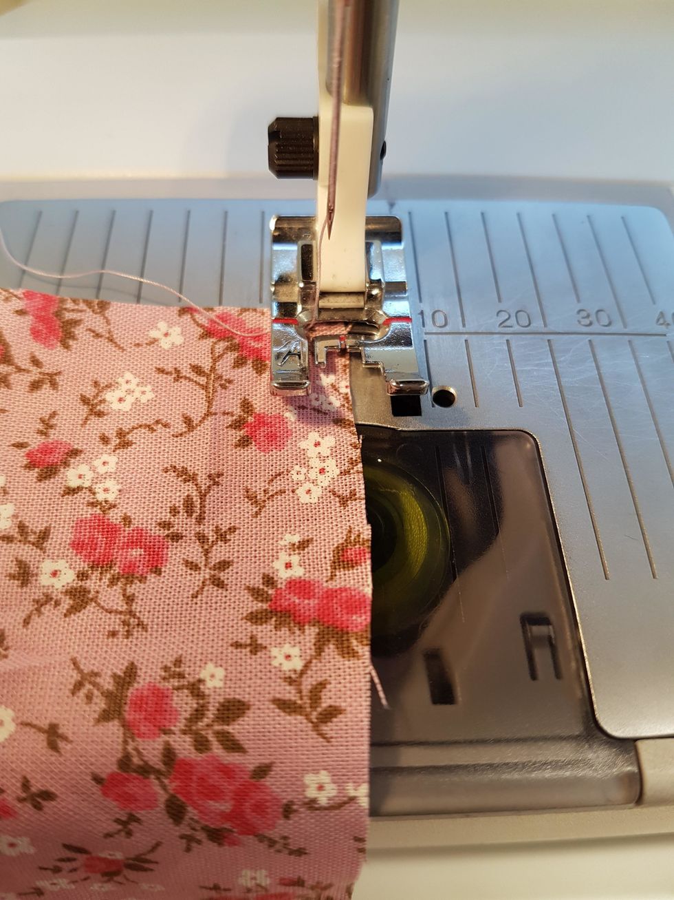 Kanten p\u00e5 tyget ska vara vid det r\u00f6da strecket. Halva stygnet g\u00e5r utanf\u00f6r tyget.