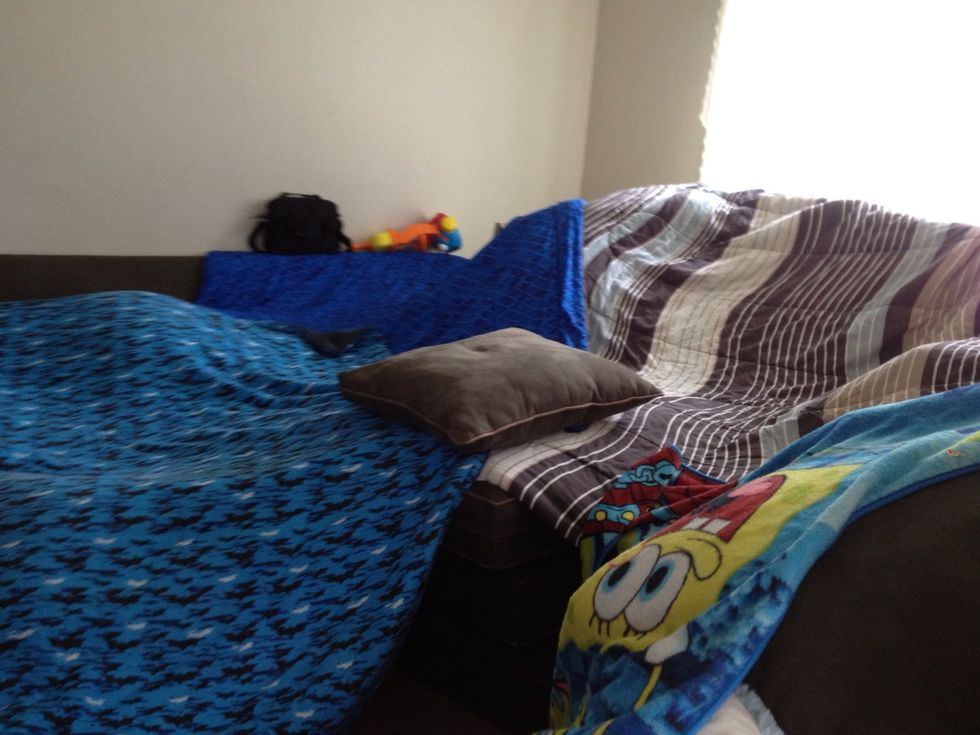 Keep one couch cushion to place on top of the blankets on the pillar. Drape the other edges over the furniture.