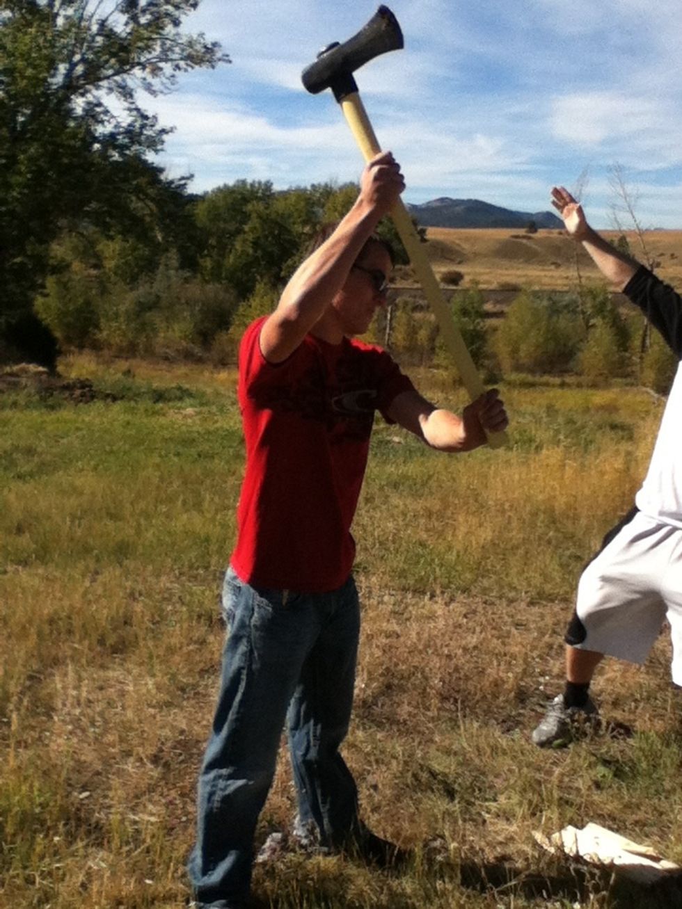 Keep the axe to your side and bring it up and over your head. Use force and split. Center it on the cracks identified in step one.