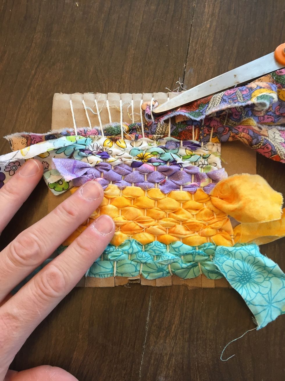 Keep weaving, taking care not to pull too tightly against the warp -- this can create an "hourglass" shape. Towards the end, you can use something to help push the fabric through.