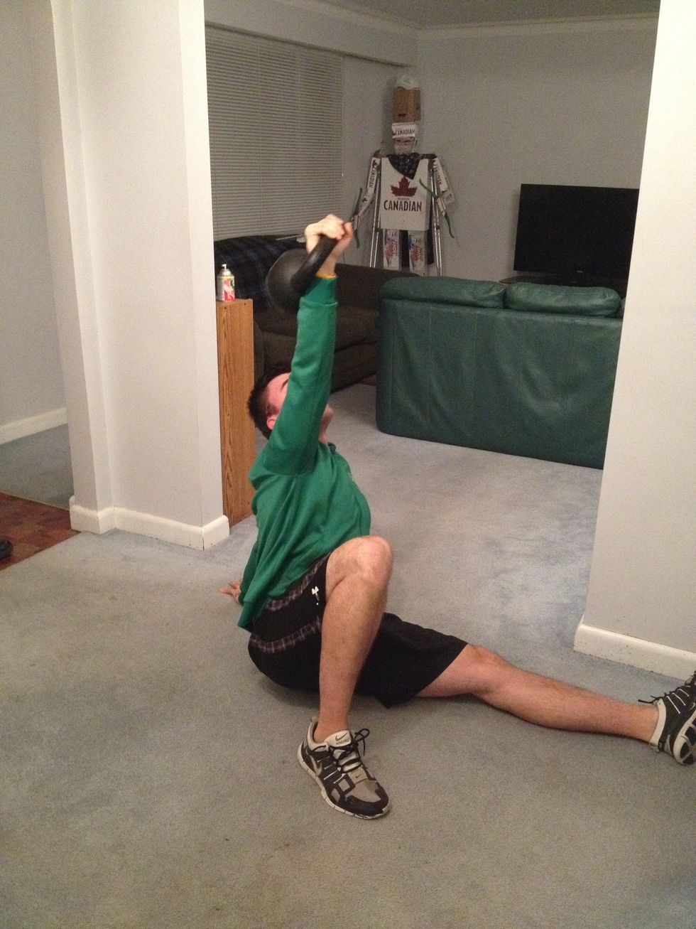 Keeping arm extended and kettlebell overhead, sit up