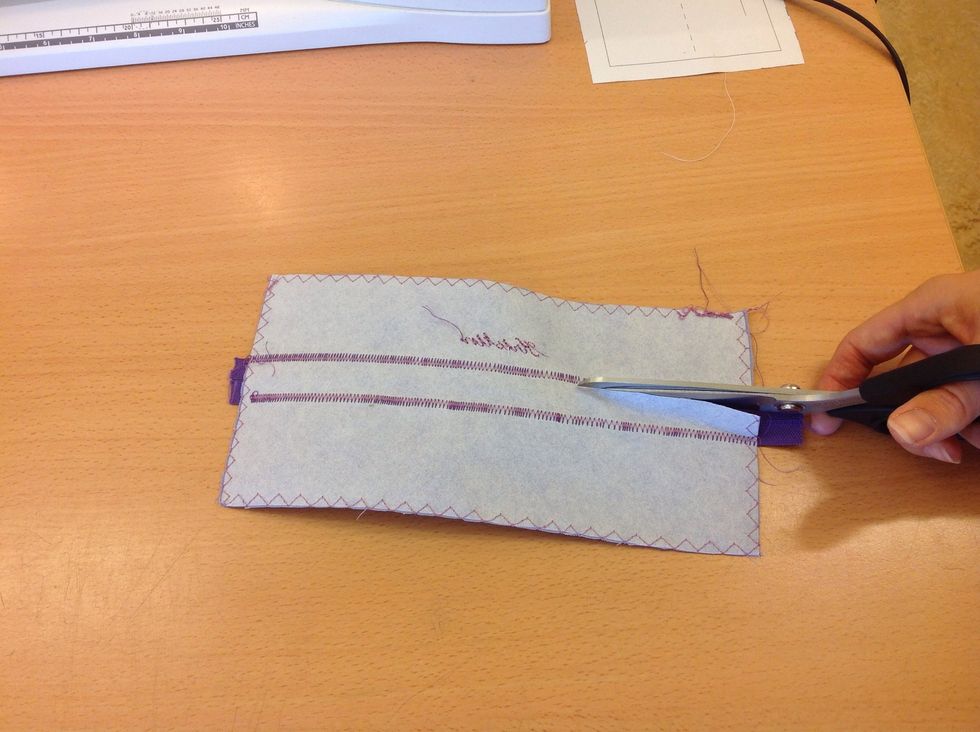 Klipp bort tyget p\u00e5 baksidan av dragkedjan. Var f\u00f6rsiktig s\u00e5 du inte klipper i dragkedjan eller s\u00f6mmen. Se p\u00e5 n\u00e4sta sida hur det ska se ut n\u00e4r det \u00e4r klart.