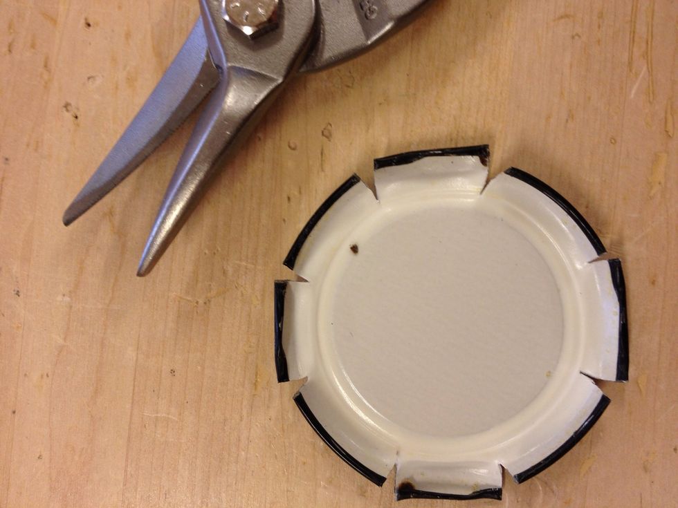 Klipp symmetriskt runt hela locket. Anv\u00e4nd en pl\u00e5tsax eller en bultsax.