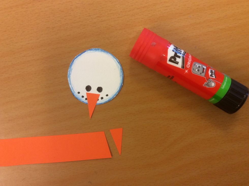 Klipp ut en n\u00e4sa i orange papper.  Limma fast.