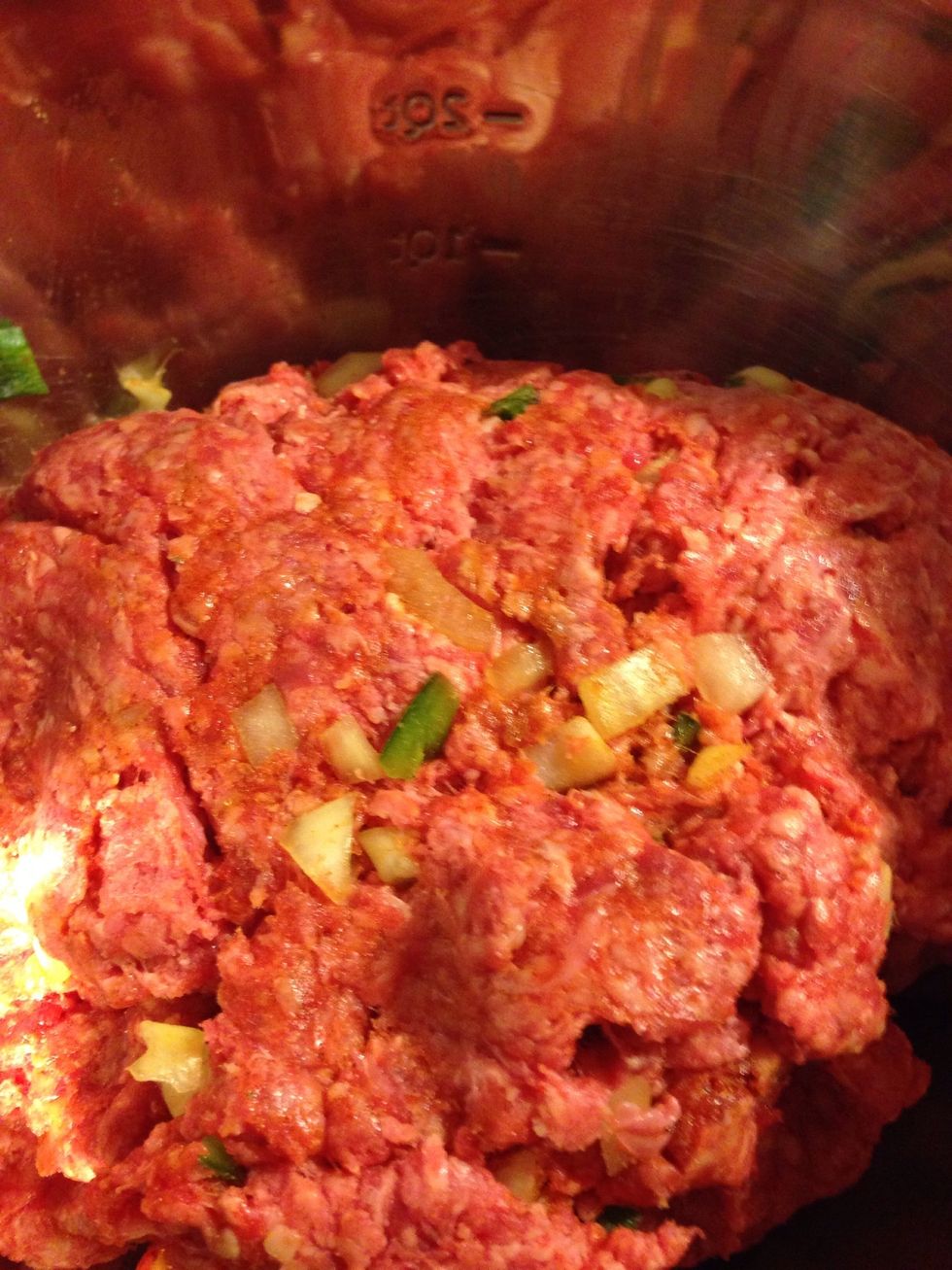 Knead ground beef, peppers, onions and seasoning together in bowl.