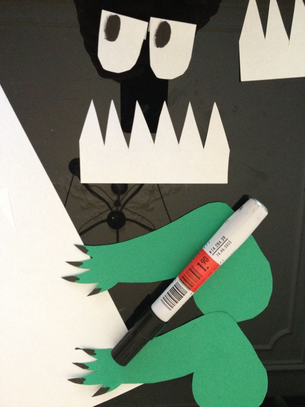 Knip ook 6 rijtjes tanden en 2 ogen uit wit papier. Teken pupillen en nagels met een zwarte stift