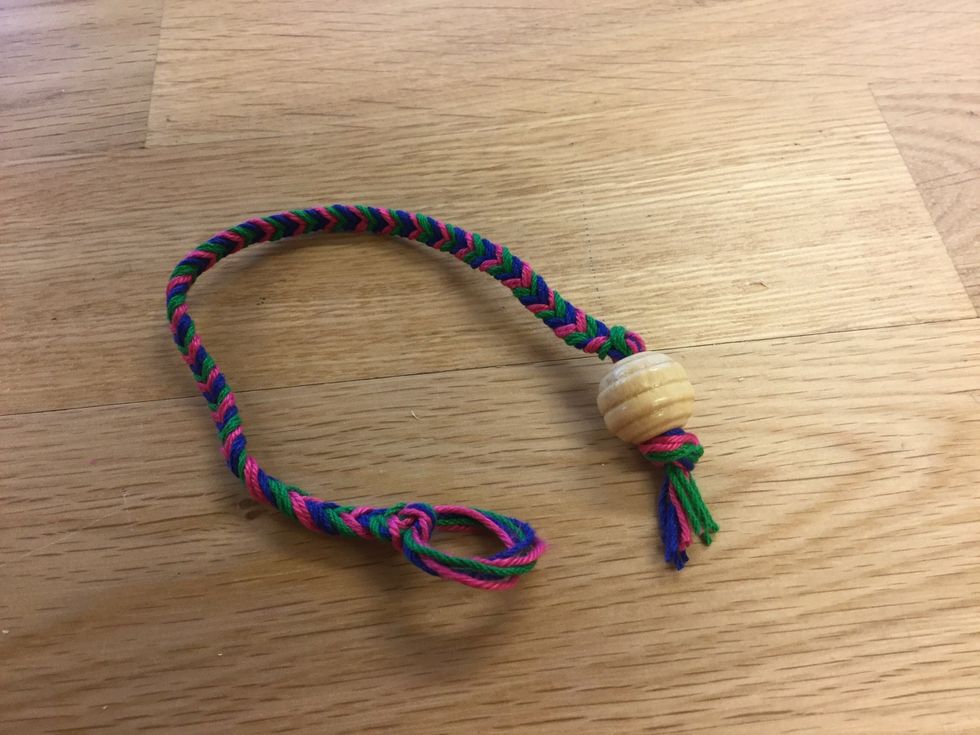 Knyt en knut f\u00f6r att fixera p\u00e4rlan. Klipp av resterande garn\u00e4ndar.