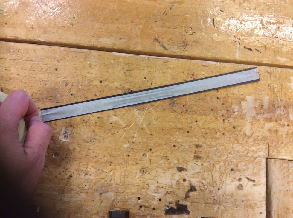 L\u00e4gg blomstertr\u00e5den p\u00e5 pappremsan och tejpa fast den. Det blir l\u00e4ttare om du ber en kompis hj\u00e4lpa dig att trycka fast tejpen medan du str\u00e4cker ut den.