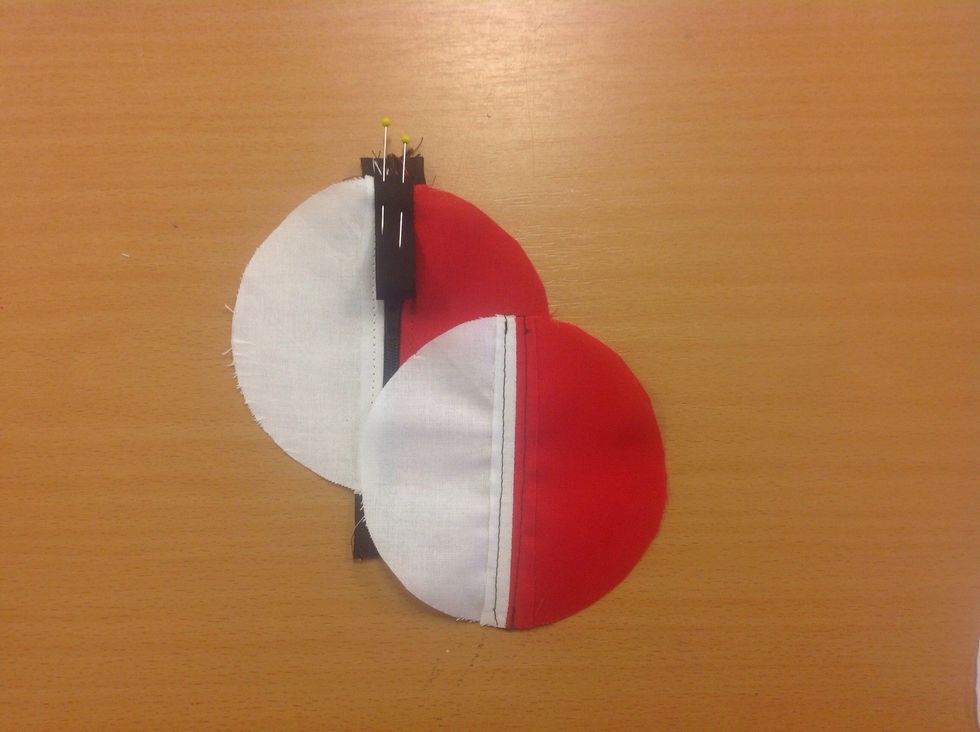 L\u00e4gg de tv\u00e5f\u00e4rgade bitarna ovanp\u00e5 varandra r\u00e4ta mot r\u00e4ta. T\u00e4nk p\u00e5 att passa in dragkedjan med det svarta bandet p\u00e5 bakstycket.