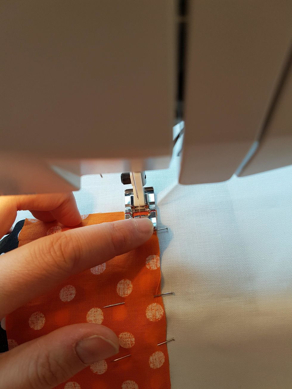 L\u00e4gg in arbetet i symaskinen. Pressarfotskanten ska f\u00f6lja kanten p\u00e5 de tv\u00e5 tygbitar du ska sy ihop.