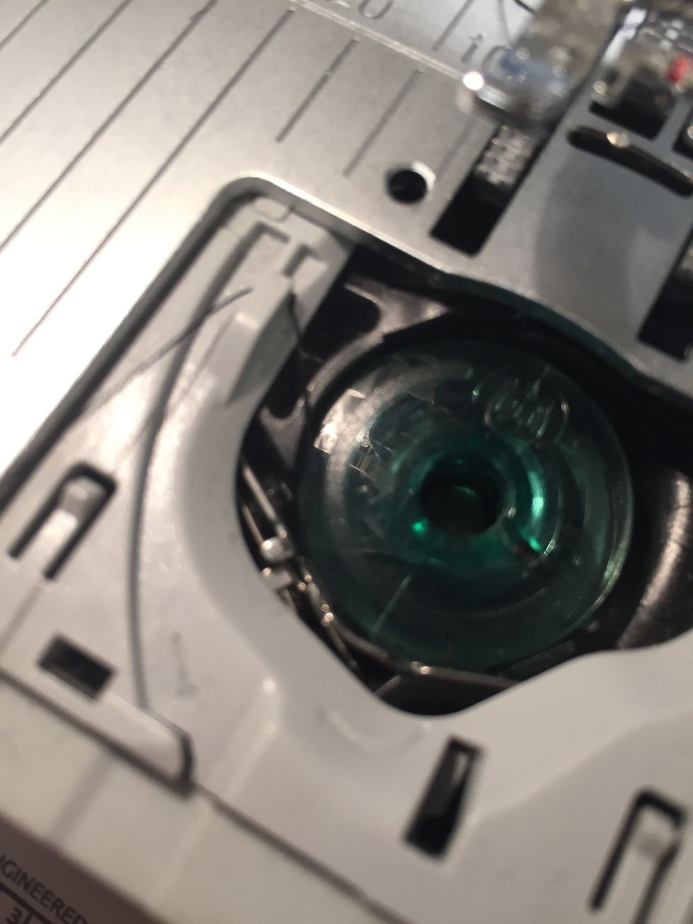 L\u00e4gg ner tr\u00e5drullen i h\u00e5let. Led upp tr\u00e5den i sk\u00e5ran som \u00e4r mot dig. Led sedan tr\u00e5den vidare upp runt den gr\u00e5 delen upp till v\u00e4nster.