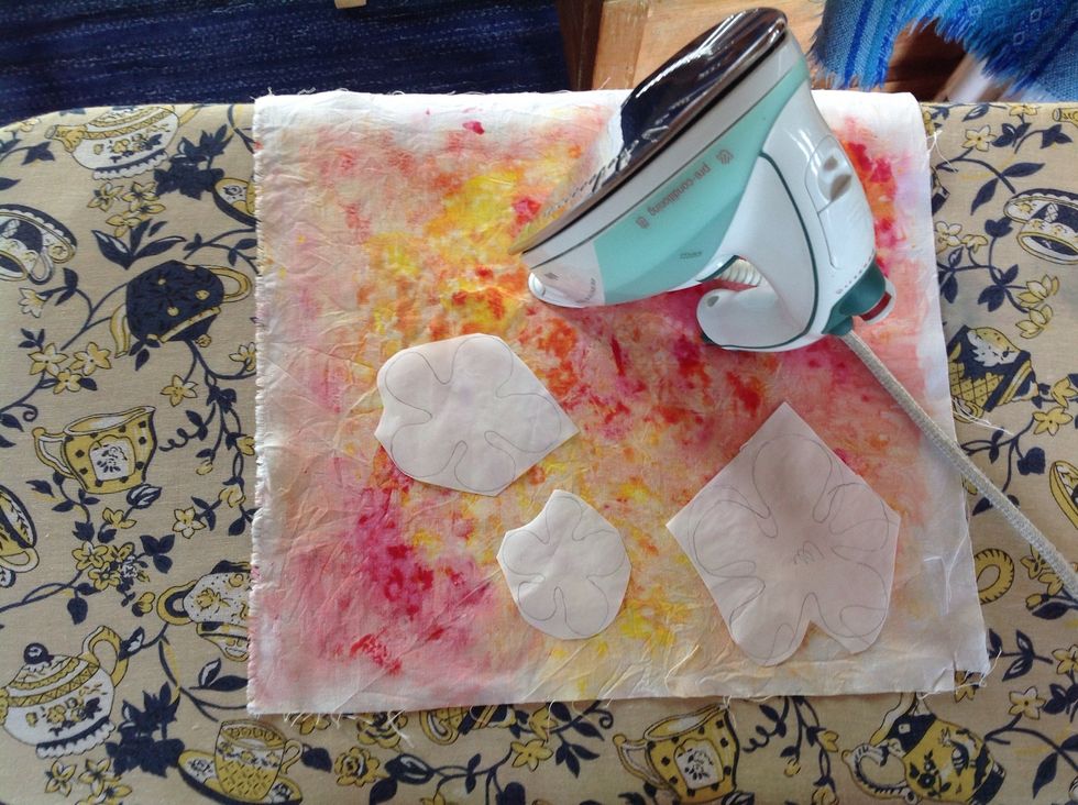 L\u00e4gg ut vliesofixbitarna p\u00e5 det tyg du vill anv\u00e4nda. T\u00e4nk p\u00e5 att l\u00e4gga vliesofixbiten med den knottriga sidan ner mot tyget avigsida ( den fula sidan p\u00e5 tyget). Visa Maria. Stryk fast bitarna.