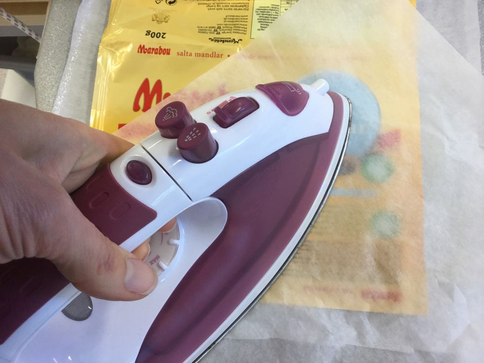 L\u00e4gg vlieseline med klistret (blank sida) upp, chokladpappret ovanp\u00e5 med vita sidan ner. L\u00e4gg bakpl\u00e5tspapper ovanp\u00e5 och stryk med l\u00e5g v\u00e4rme p\u00e5 strykj\u00e4rnet. Ta det f\u00f6rsiktigt s\u00e5 plasten inte sm\u00e4lter!