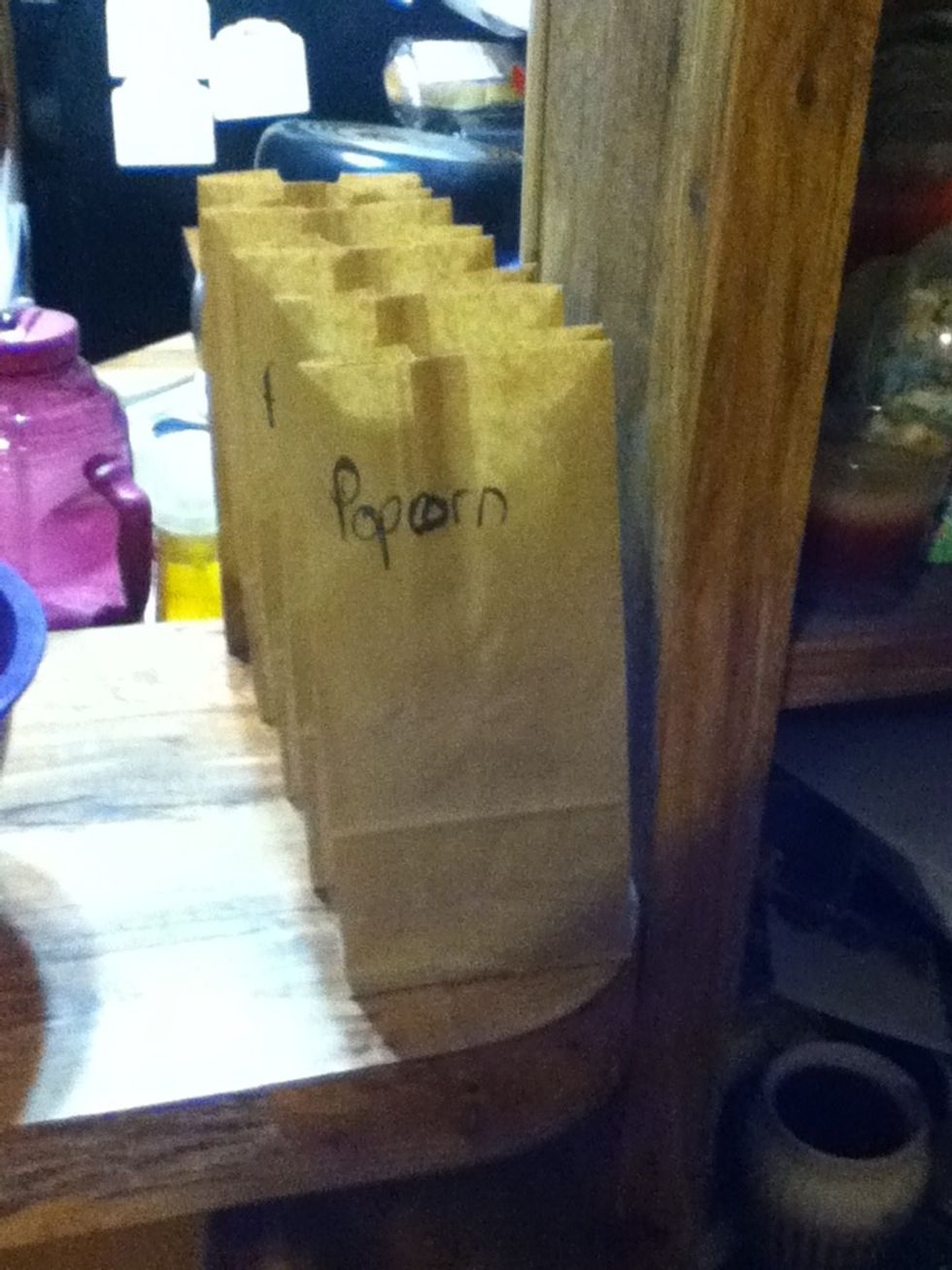 Label brown paper bags popcorn and set out on a counter or table