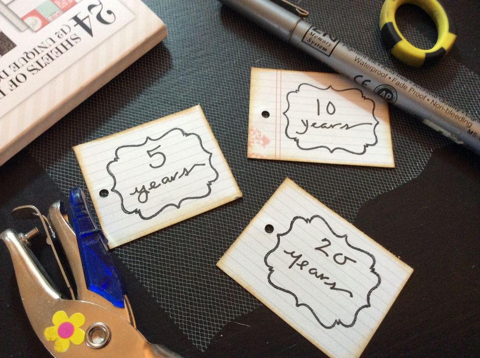 Label with years and punch a hole in each tag.