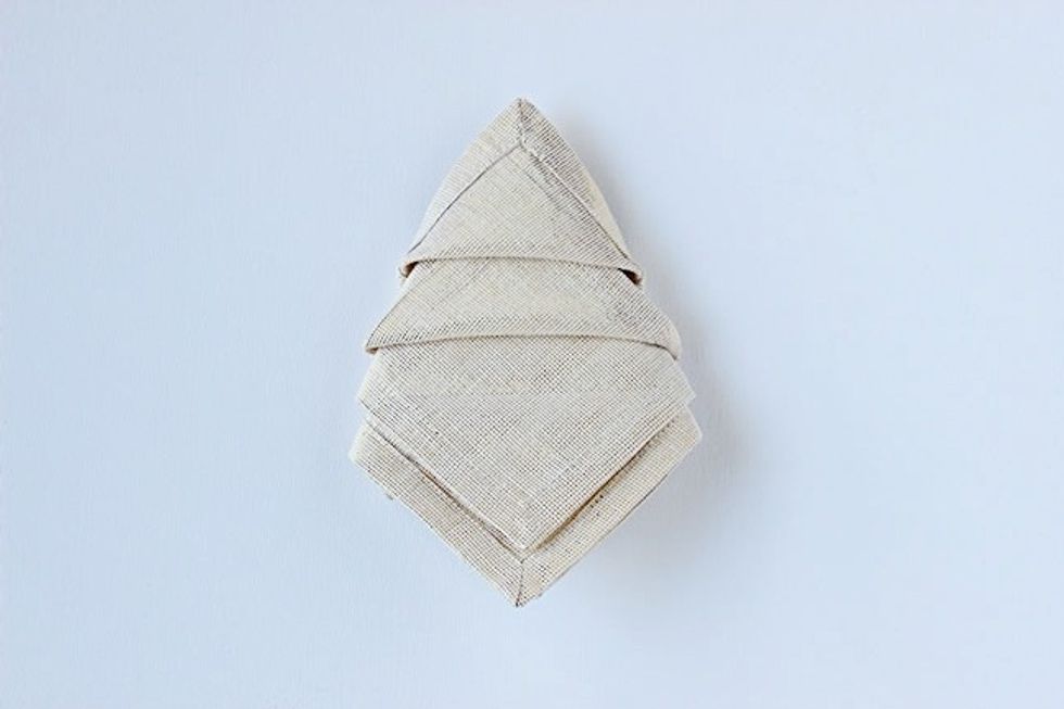 Lastly, form the pointed tree top by folding the top layer upward, Continue folding upwards for the rest of the layers but tuck the point into the folded layer above it.