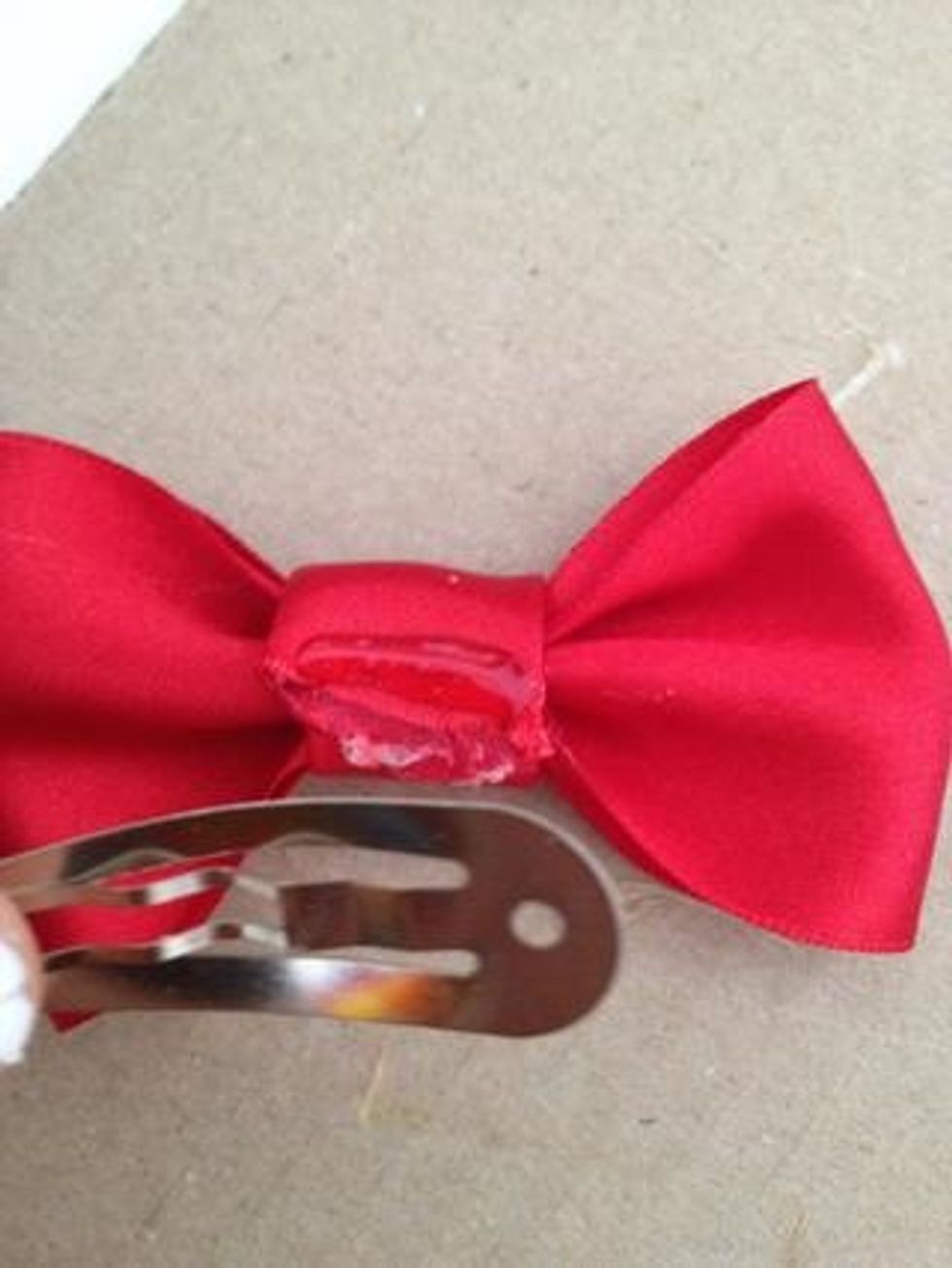 Lastly, place a small line of hot glue on your wrapped ribbon. Take a clip, alligator clip, bobby pin, or even a ponytail tie, and place it on the hot glue.