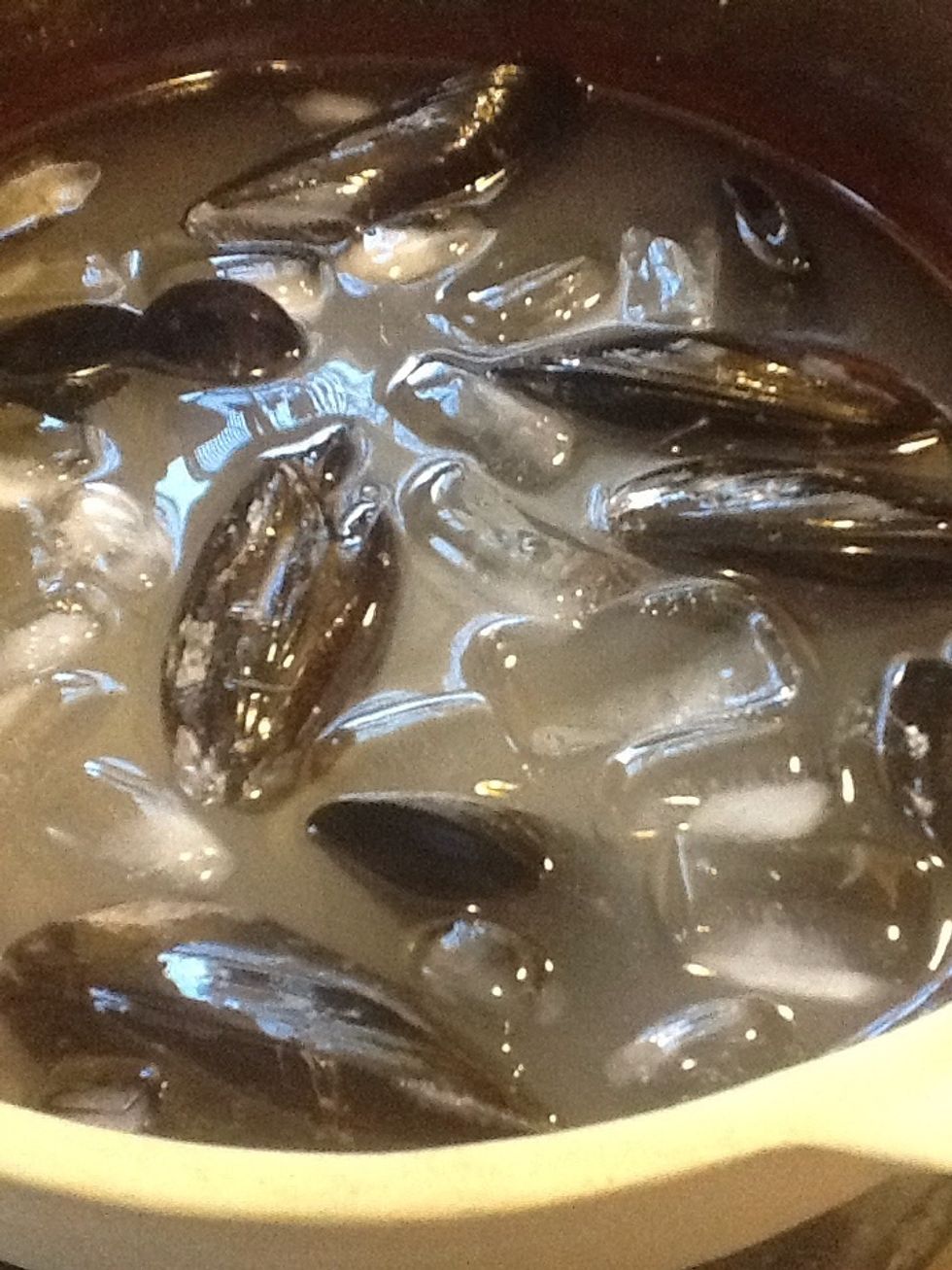 Lava y limpia los mejillones y las almejas en un ba\u00f1o de agua fr\u00eda con sal