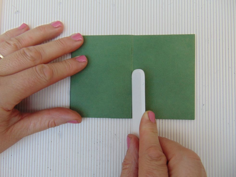 Lay down flat & using a score tool gently score along fold on the single page to stretch paper fibres, whilst doing this start to fold the single page over to the other 3 pages to create mini album...