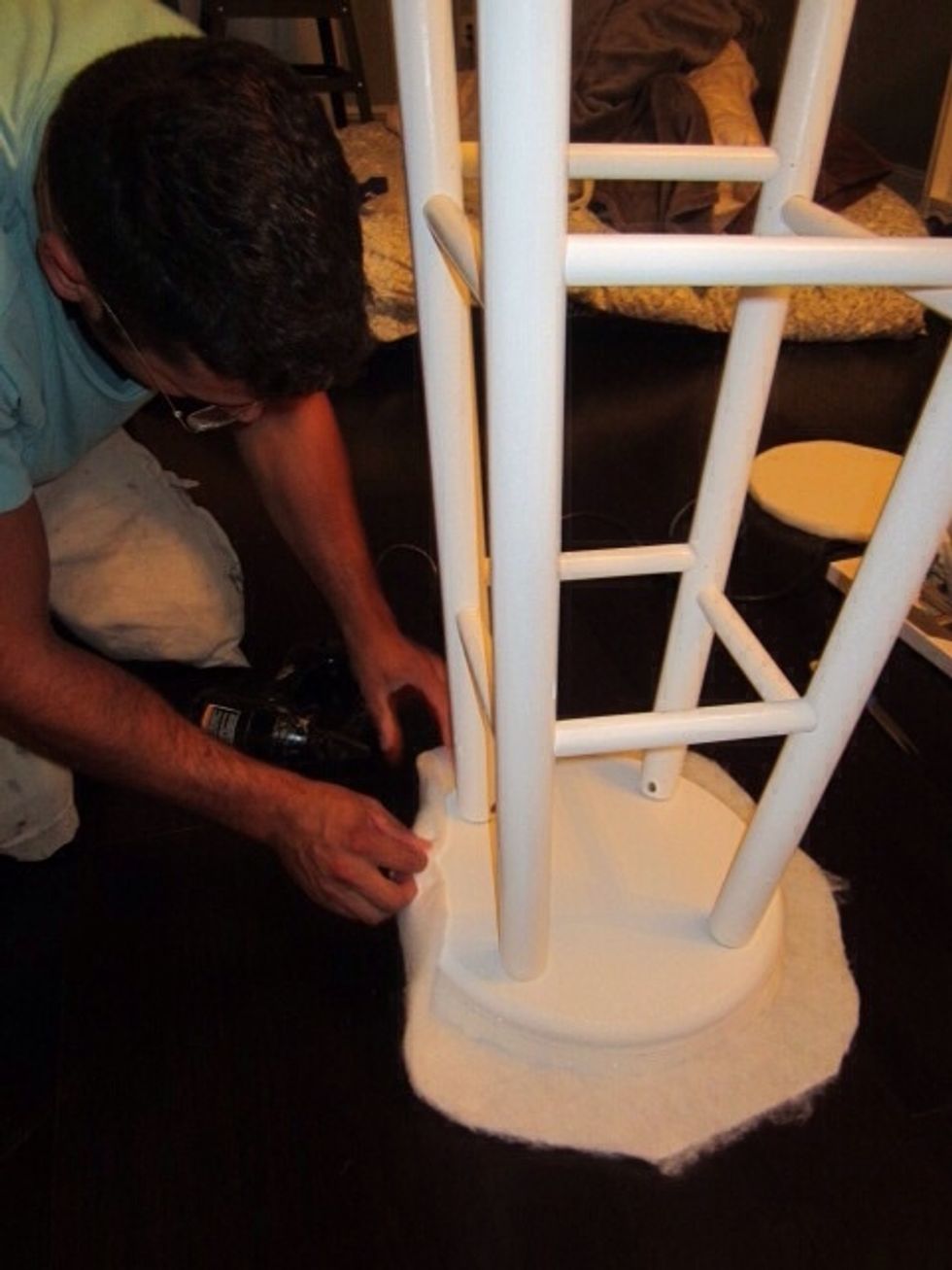 Lay down the batting, then the foam pad and last the stool upside down on top. Using the staple gun start working your way around pulling the batting tightly. Fold the edges under for a finished look.