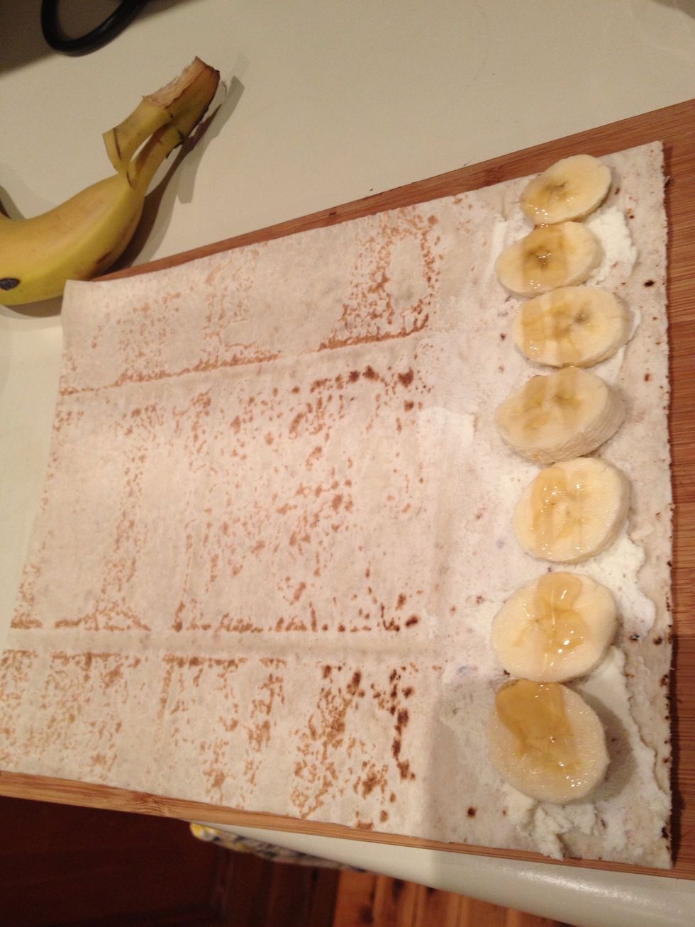 Lay down your wrap. I use Rye Mountain Bread, which is nice and thin and rolls up easily. Place ricotta along one edge, amount to your liking. Top with sliced banana in a line, and drizzle with honey.