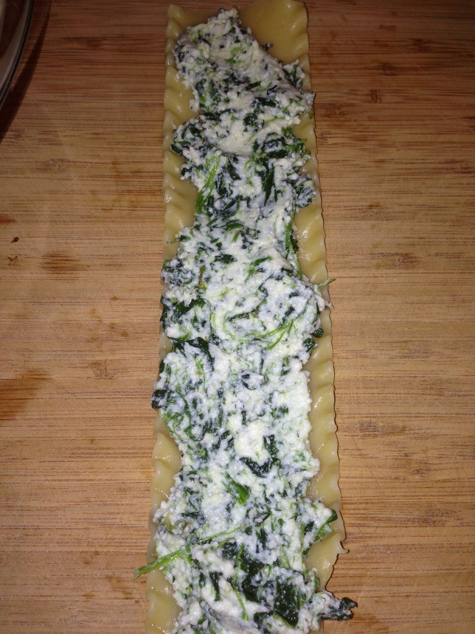 Lay lasagna noodle on a dry surface. Spread about 1 1/2 tbsp of the filling in a thin layer on the noodle. Starting from one end, delicately roll the noodle, and place on sauce in casserole dish.