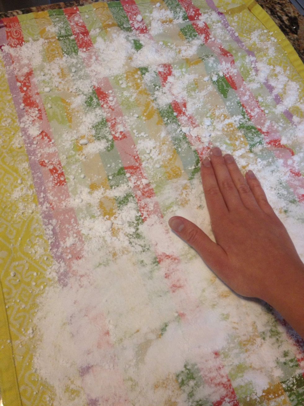 Lay out a large, clean dish towel on the counter and cover completely with powdered sugar.