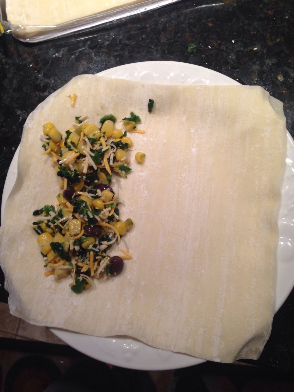Lay out an egg roll wrapper and scoop some of the mixture near the edge.