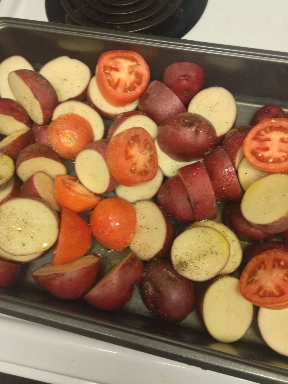 Lay out potatoes and tomatoes on the pan. Drizzle some olive oil and some salt and pepper.