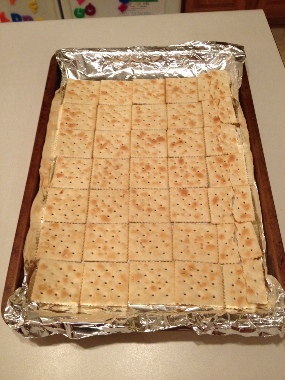 Lay out saltine crackers across the foil. Use cracker pieces to fill in edges if necessary.