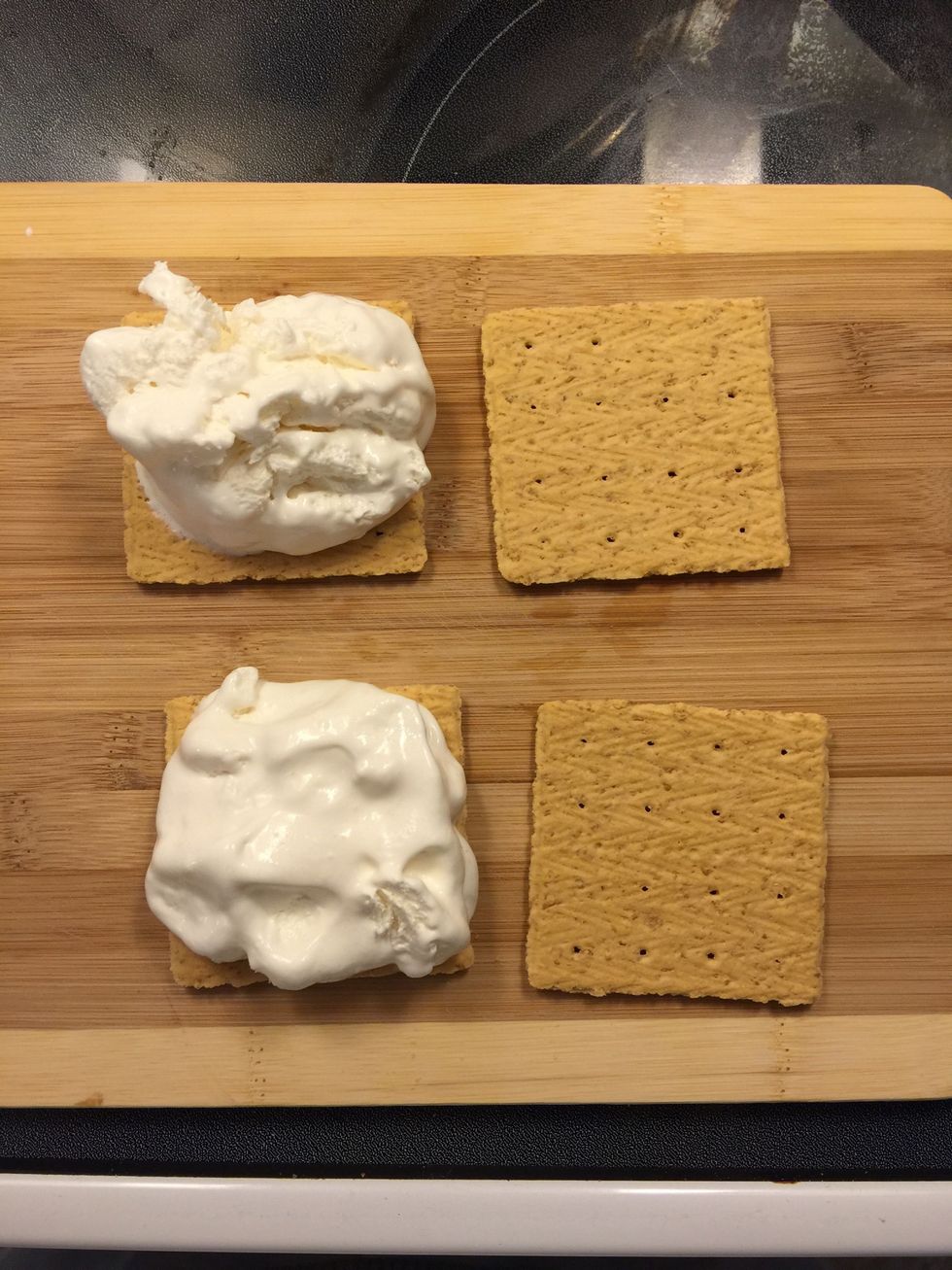 Lay out the 4 graham crackers faced down. Place two tablespoons of light whipped topping on 2 crackers.