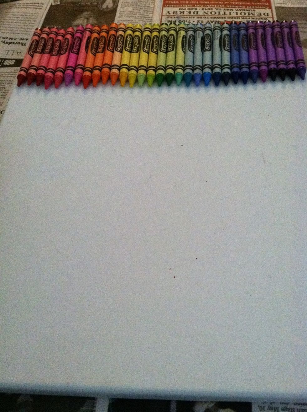 Lay out your colors as desired, and, using your glue gun, glue them to the top of the canvas (leave paper on crayons)