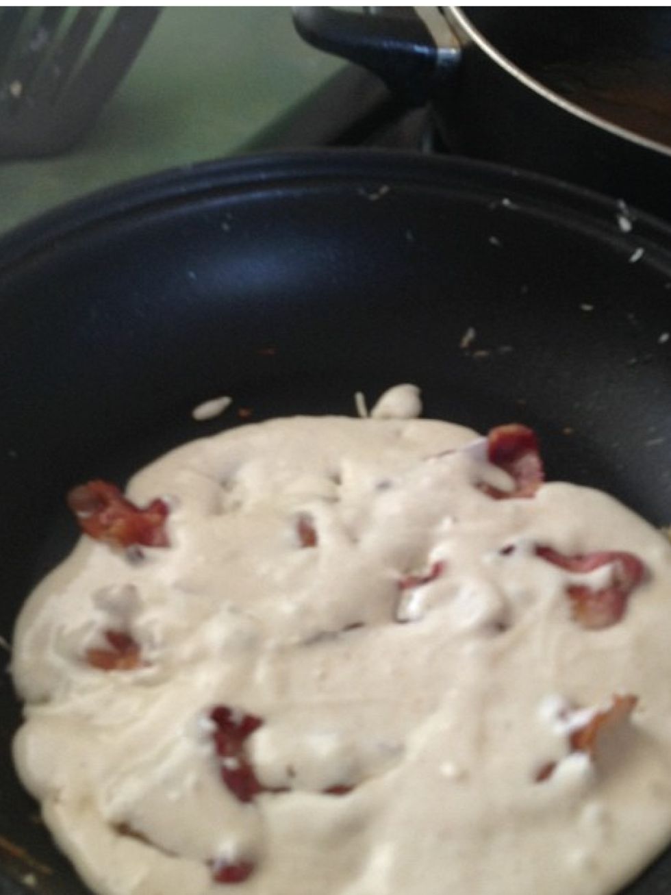 Lay the bacon pieces on the pancake, then push them further in the pancake with a fork so the pieces of bacon will have batter on both sides.