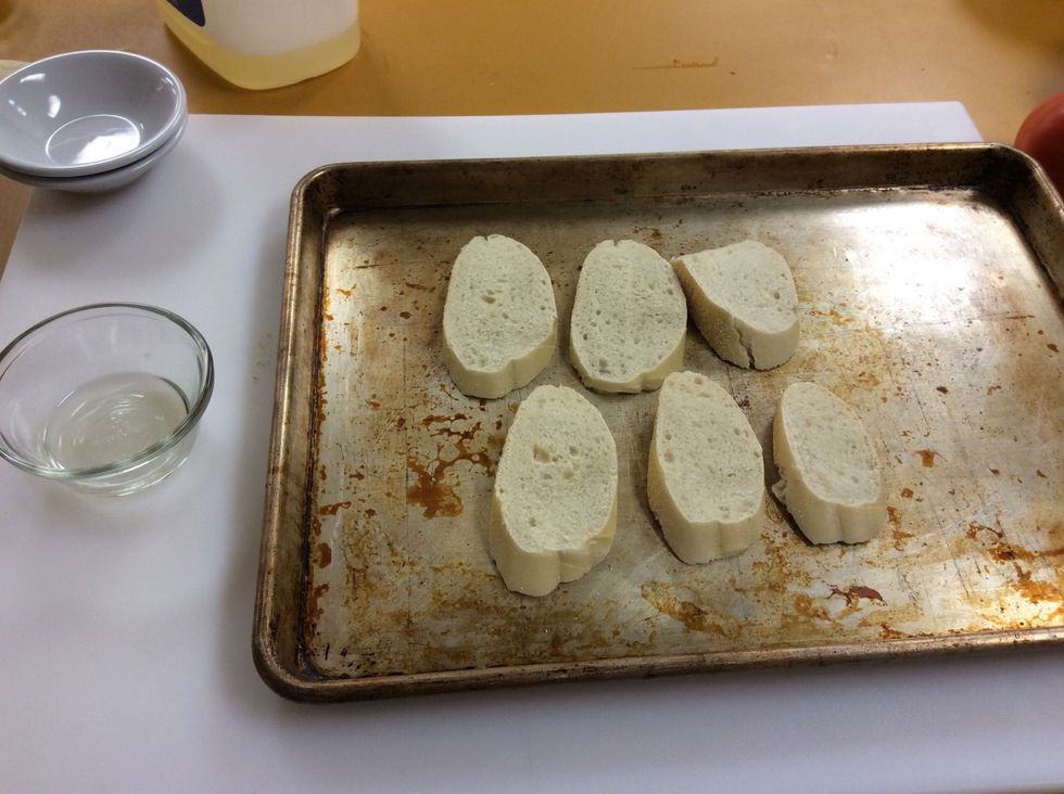Lay the bread out on a sheet tray with nothing under it. You will be broiling the bread, a substitution for toasting.