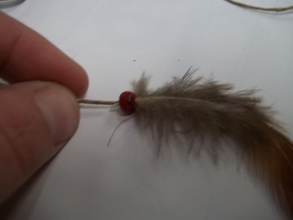 lay the feather on the glue and slide the bead over the end of the feather. Allow to dry. If your bead is too lose you will need to tie a knot.