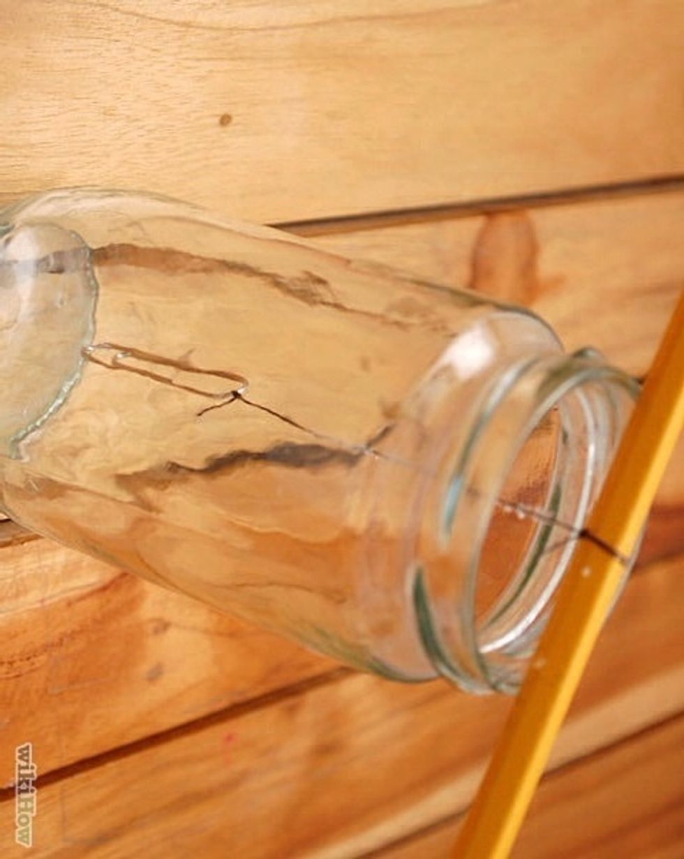 Lay the stick over the top of the glass jar so that the string hangs down inside the jar, but doesn't touch the bottom of the jar