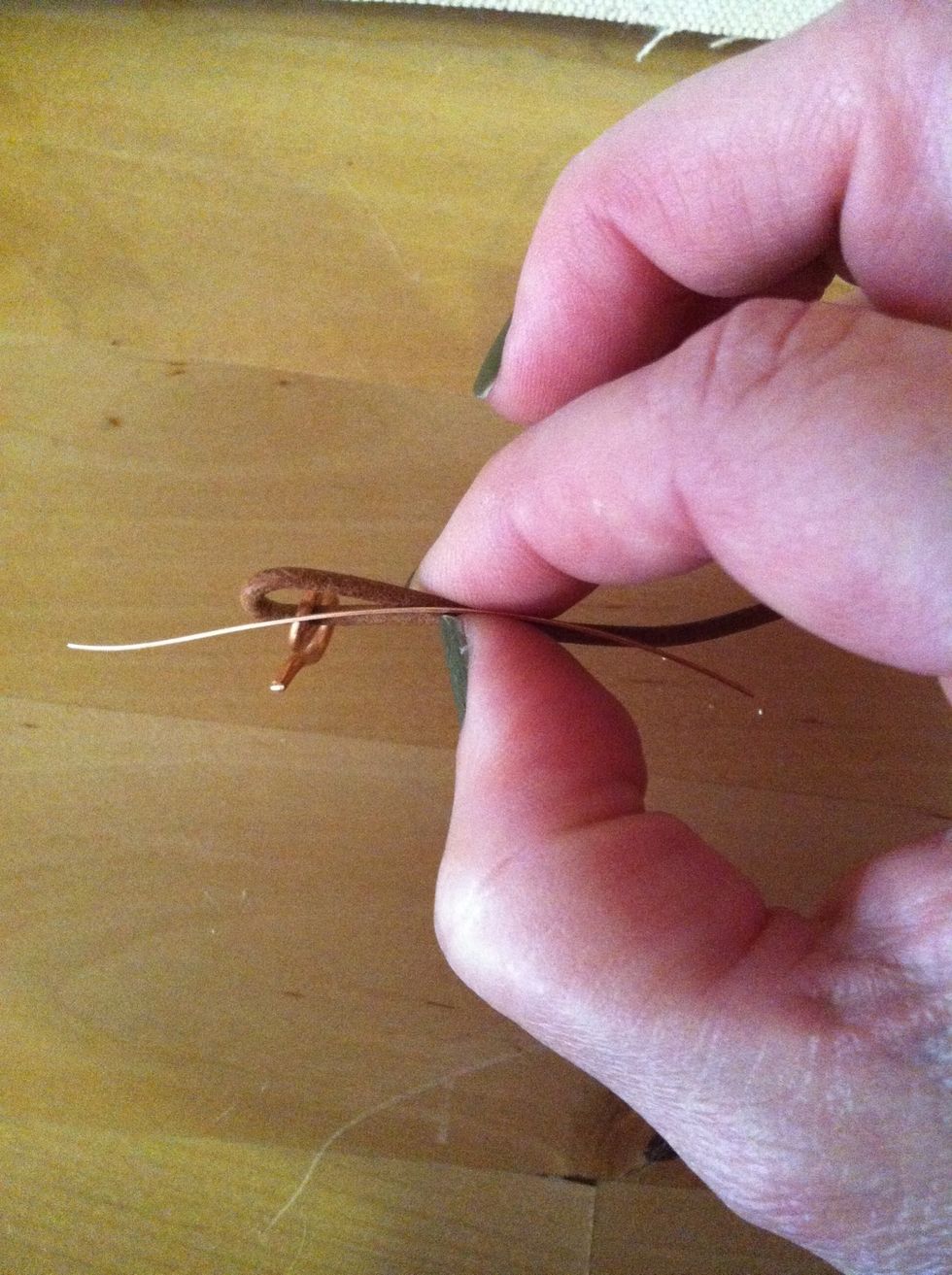 Lay the wire along the loop of leather and pinch everything together with your fingers. There should be about half of the wire sticking out from both ends underneath your fingers.