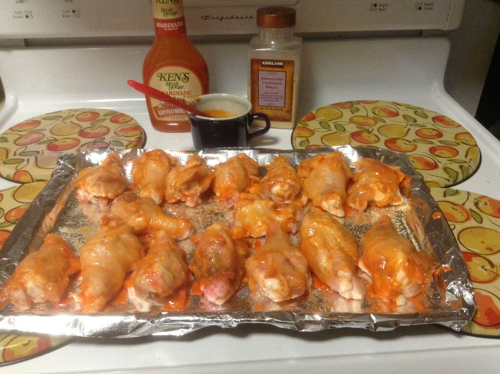 Lay tin foil down over a sheet pan, spray with cooking spray, lay chicken wings down, brush with sauce then sprinkle with garlic powder. Bake at 350\u00b0