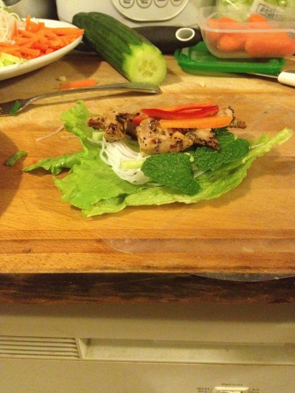 Lay wrapper flat. In a row across the center, place the lettuce first, then a handful vermicelli, mint, chillies, meat, carrot & cucumber. Fold uncovered sides inward, then tightly roll the wrapper.